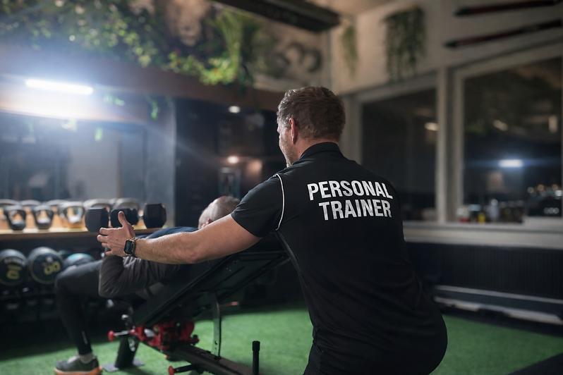 Personal Trainer a treinar um cliente num ginásio